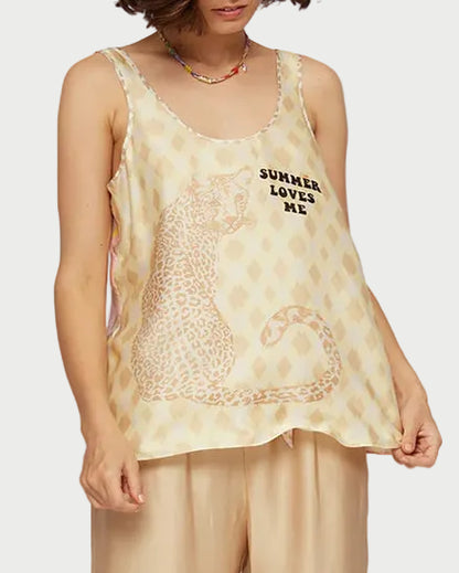 Woman wearing a beige printed  top and satin pants against a light background