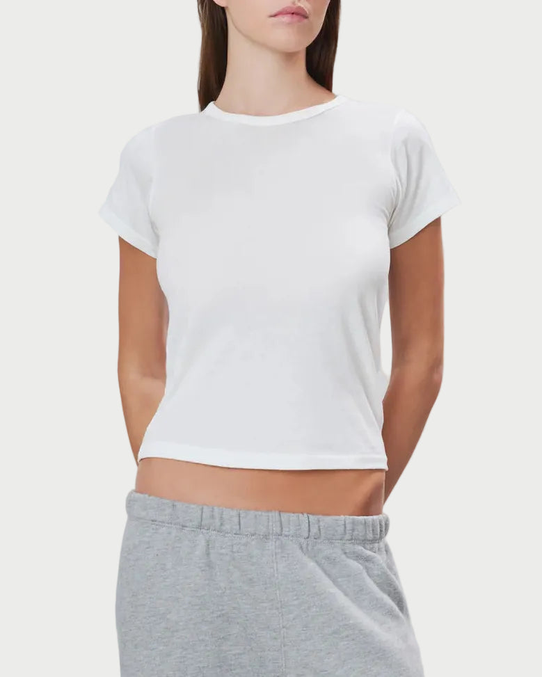 Woman wearing a white t-shirt and gray sweatpants on a light gray background