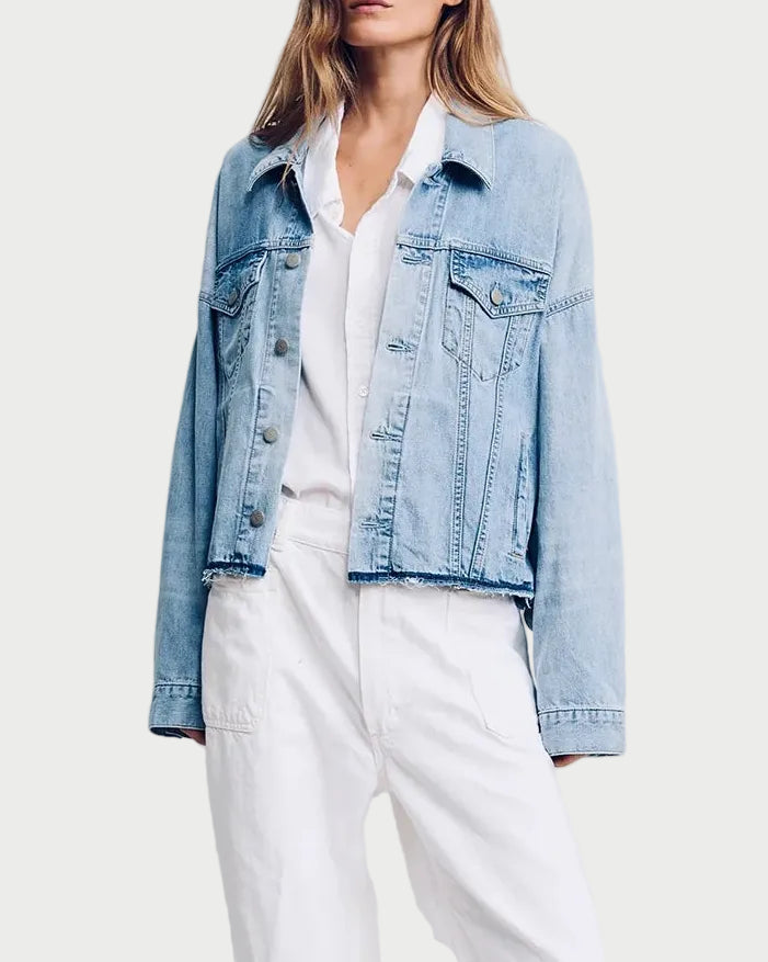 Woman wearing a light blue denim jacket over a white shirt and pants on a plain background