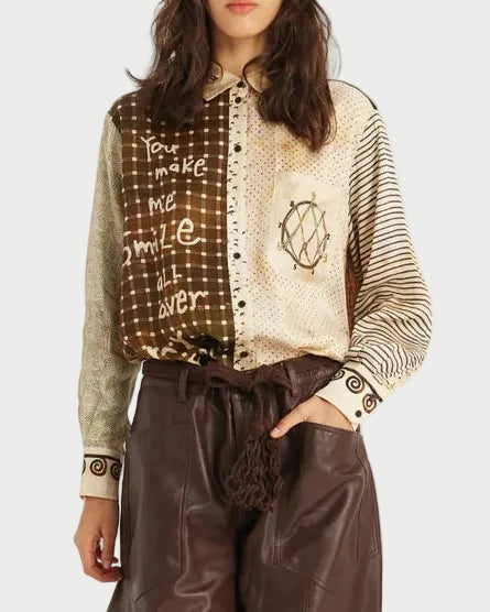 A model is shown from the head to the feet wearing a long-sleeve button-up shirt with a brown and beige patterned yoke and striped sleeves, paired with wide-leg brown faux-leather trousers and black pointed boots, against a plain white studio background.