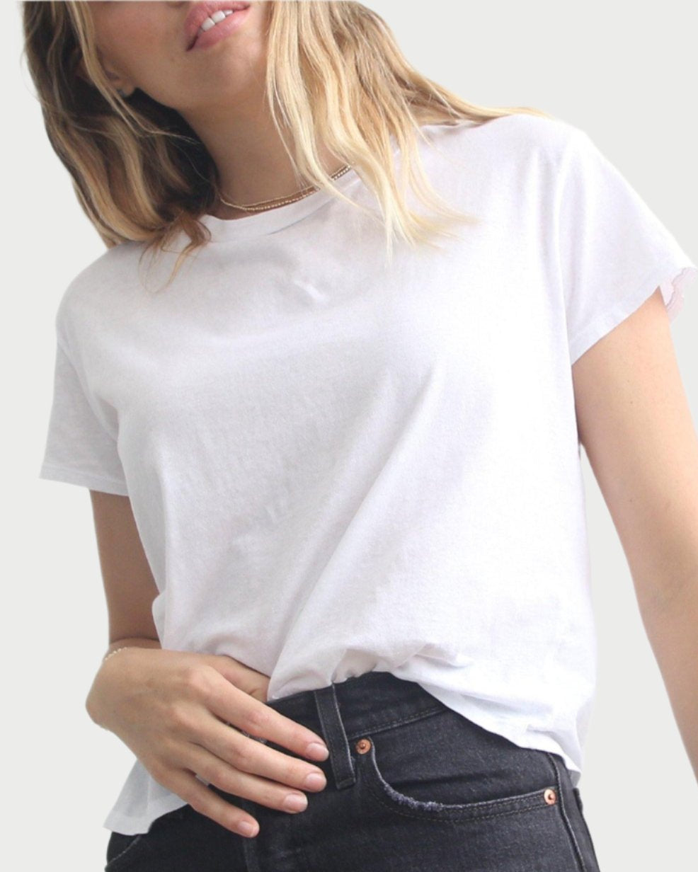 A person wearing a Harley Boxy Crew in Black and White by perfectwhitetee and black jeans stands against a plain background. Their head is partially out of frame, and their hand rests on their hip, showcasing this versatile layering piece ideal for any minimalist wardrobe.