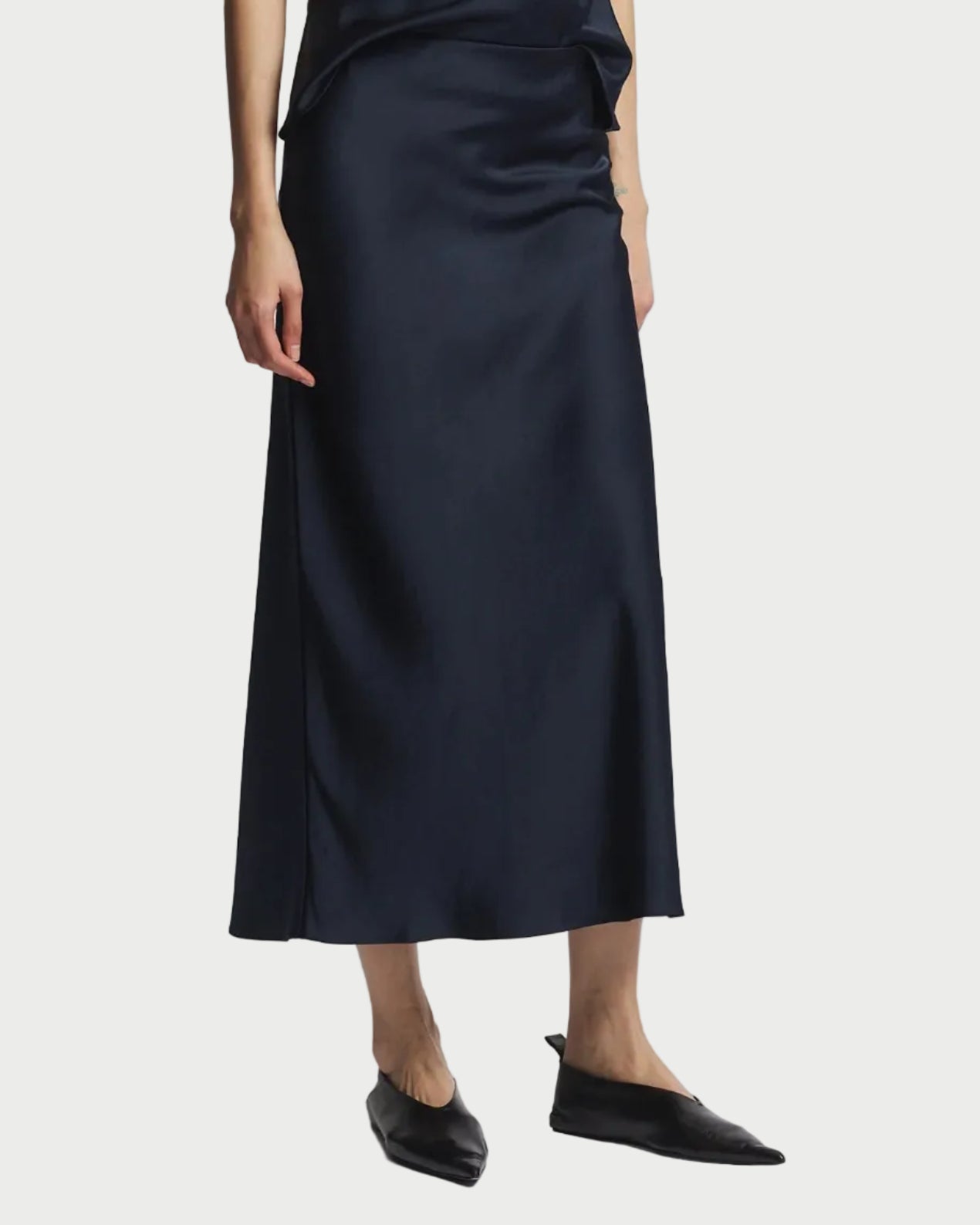 Person wearing a black slip dress on a white background