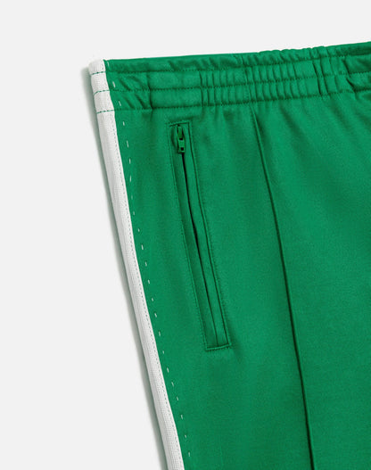 Close-up of RE/DONE’s Sunland Track Pant in green, featuring an elastic waistband, zippered side pocket, and white side stripe. Smooth fabric offers a sleek, sporty look with modern Western-inspired style.