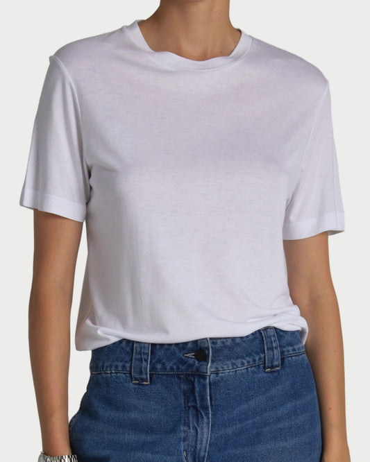 Person wearing a plain white t-shirt and blue jeans on a gray background