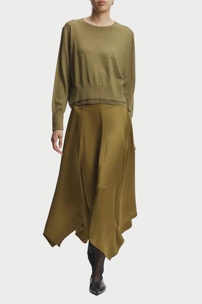 Person wearing a green outfit with a top and long skirt on a white background