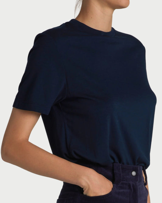 A person wearing the Saint Art Zola Crewneck Navy Tee by Saint Art NY and dark high-waisted pants, hands in pockets, shown from shoulders to hips against a plain background.