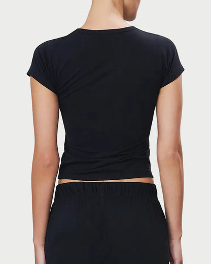 Person wearing a black cap-sleeve top and black pants on a light gray background