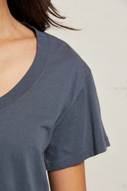 Close-up of a person wearing the perfectwhitetee Hendrix V-Neck T-Shirt Night in dark gray, highlighting their neck, shoulder, and upper chest against a plain light background.