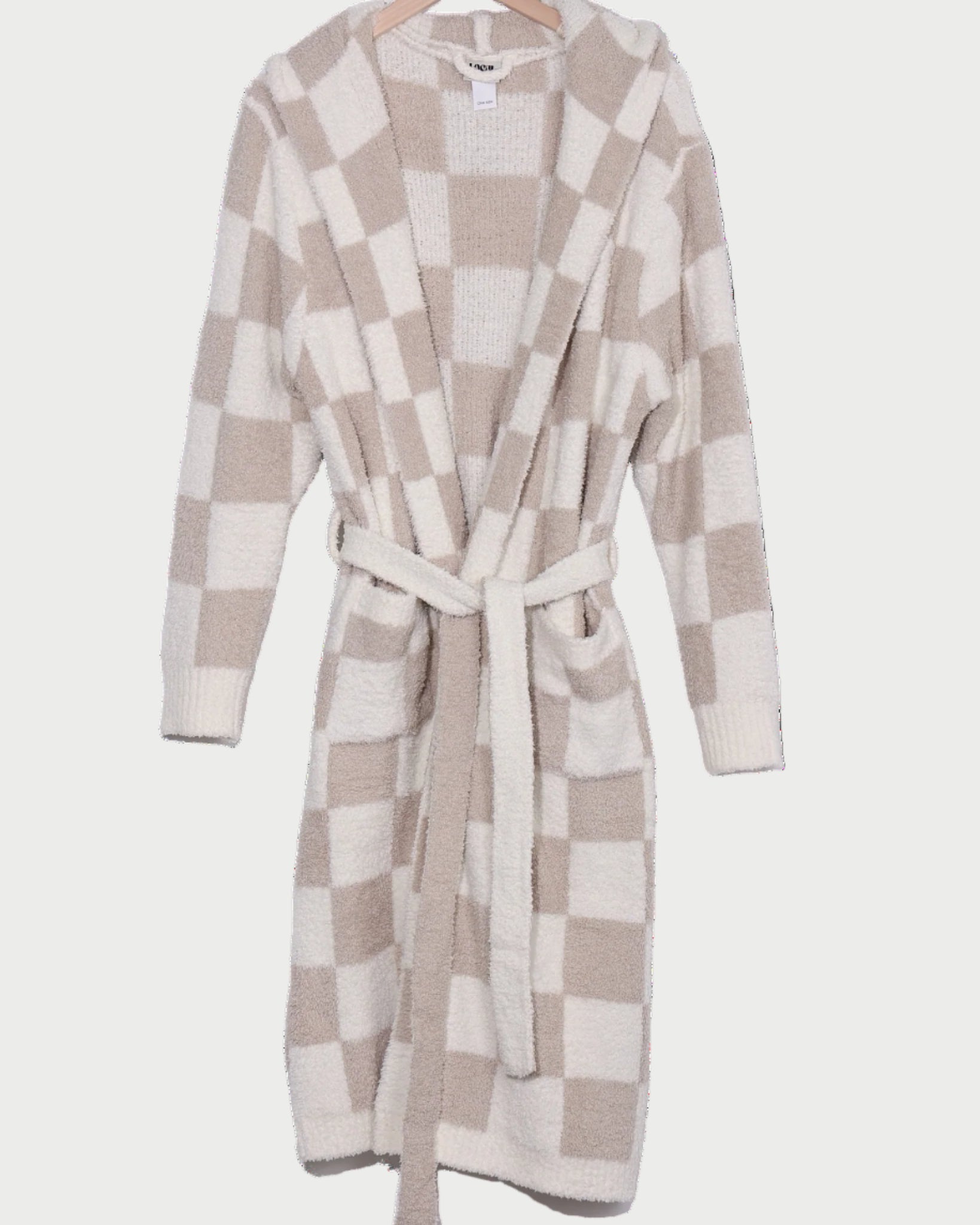 The LOCAL BEACH Sand Checker Luxe Robe—a cozy, hooded beige and white checked lounge robe with a matching belt—hangs invitingly on a wooden hanger.