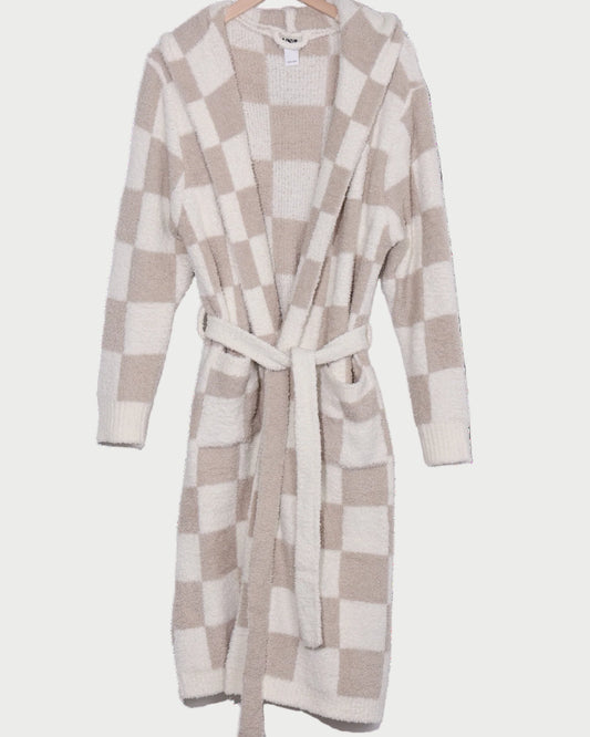 The LOCAL BEACH Sand Checker Luxe Robe—a cozy, hooded beige and white checked lounge robe with a matching belt—hangs invitingly on a wooden hanger.