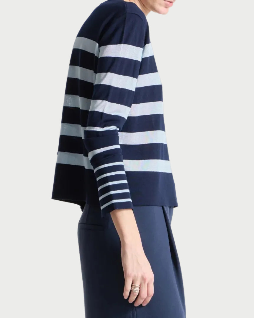 Person wearing a navy and sky striped sweater with a long navy skirt on a white background
