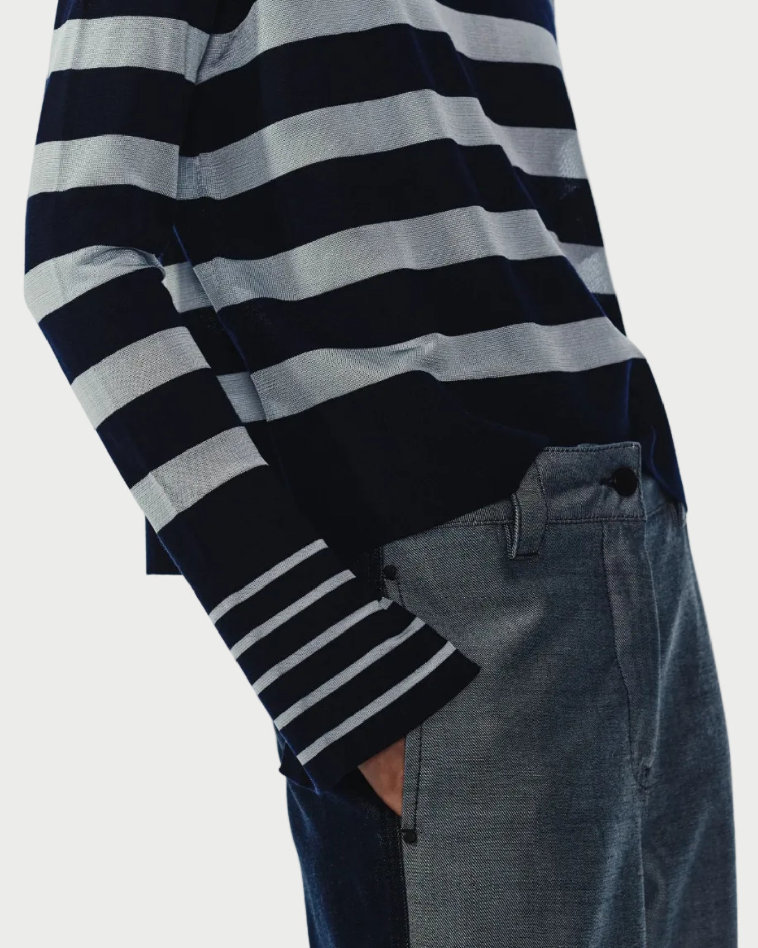 Person wearing navy and sky striped sweater and dark jeans on a light gray background