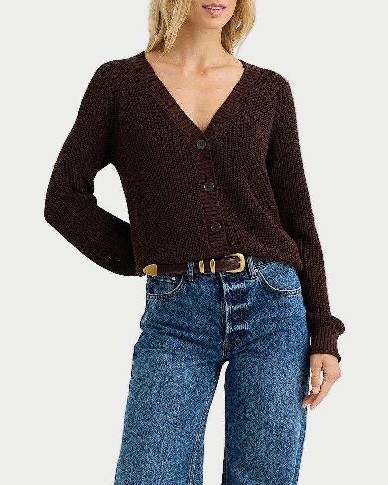 Woman wearing a brown sweater and blue jeans on a white background