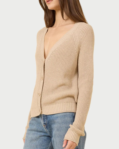 A woman models the One Grey Day Raleigh Cardigan, a relaxed fit, chunky fisherman-rib knit button-up with long sleeves, paired with blue jeans against a plain light background.