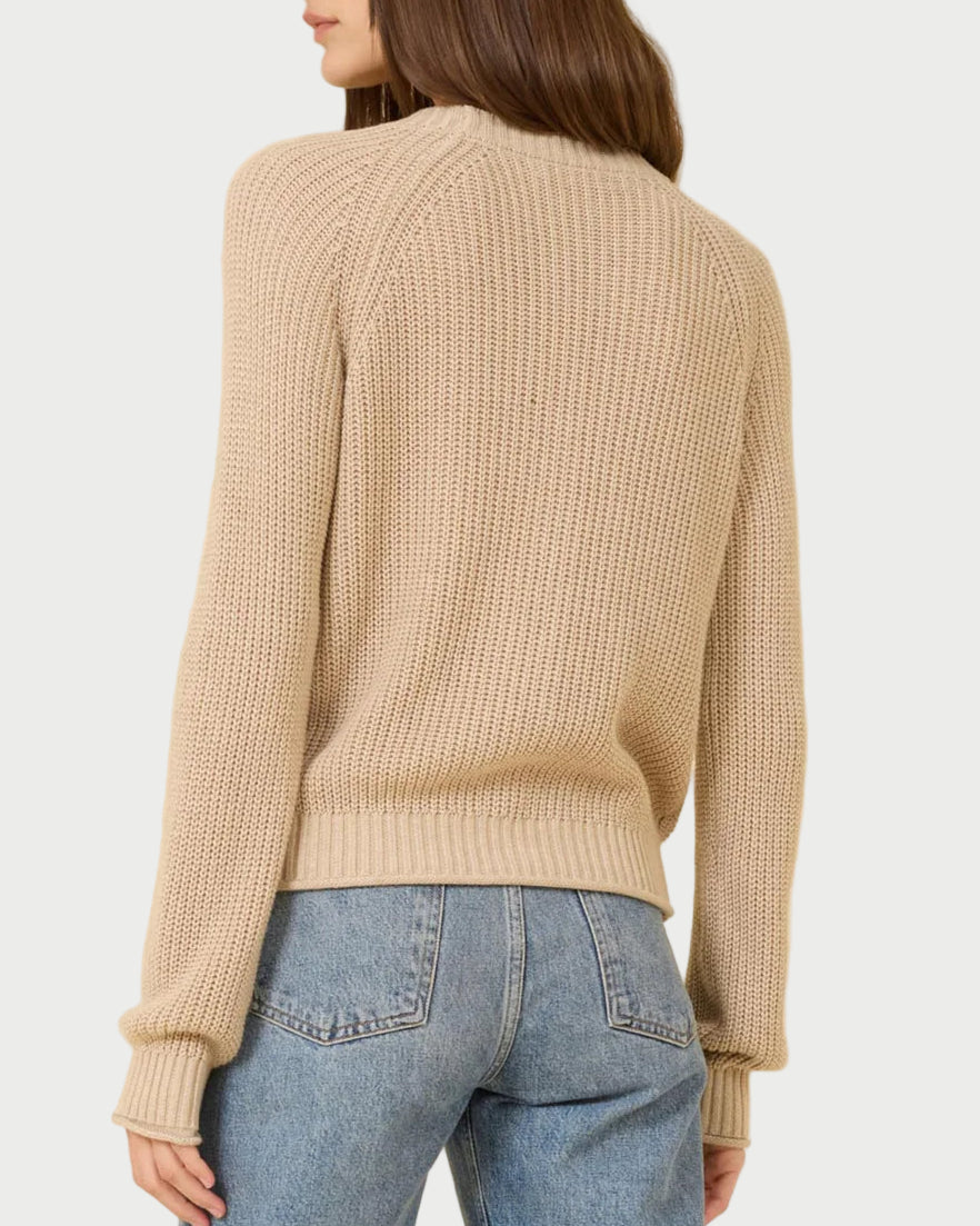 A woman with long brown hair is seen from the back wearing the One Grey Day Raleigh Cardigan, a relaxed-fit chunky fisherman-rib knit, paired with light blue jeans.