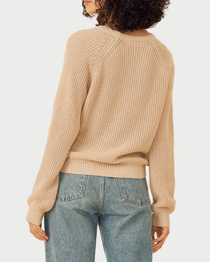 Woman wearing a beige sweater and blue jeans on a beige background