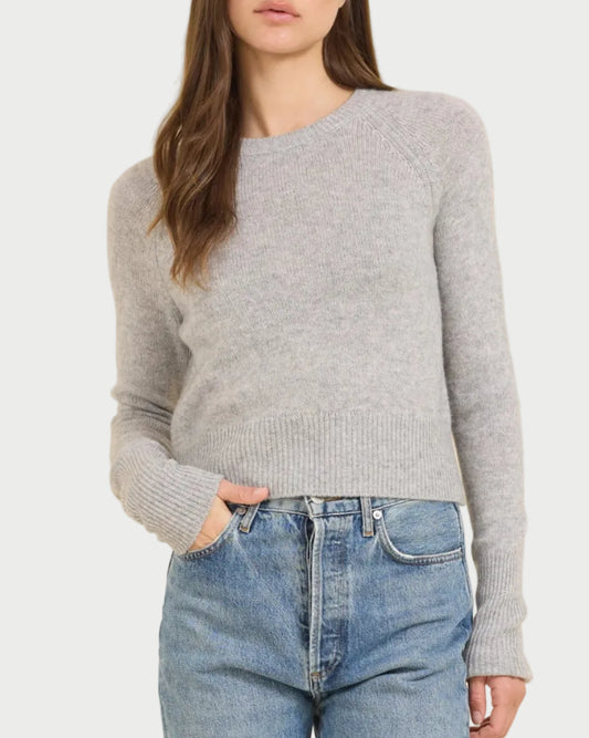 Woman wearing a gray sweater and blue jeans on a beige background