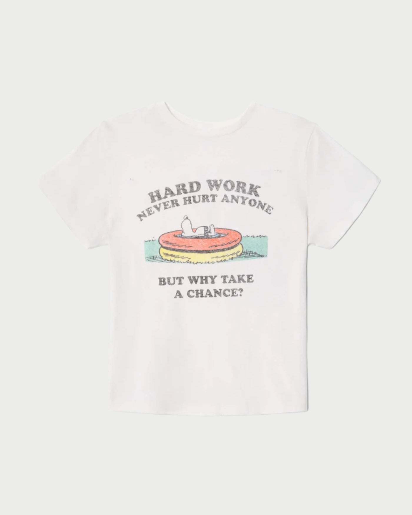 The RE/DONE Hard Work Snoopy Tee is a white shirt with a retro Peanuts graphic of Snoopy in a kiddie pool, text reading "HARD WORK NEVER HURT ANYONE" above and "BUT WHY TAKE A CHANCE?" below. Made from recycled heritage cotton.