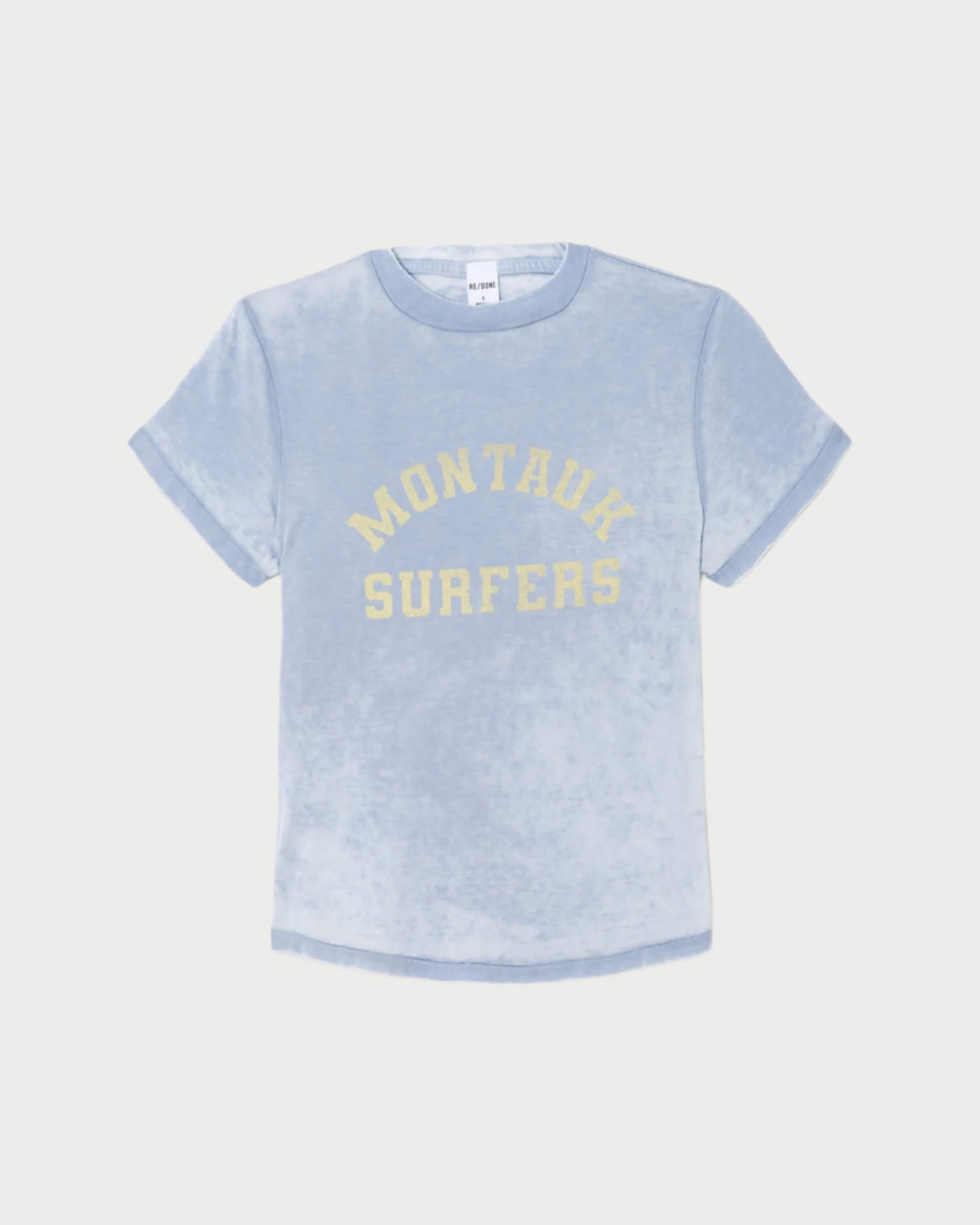 The RE/DONE Montauk Tee is a light blue, short-sleeve vintage-inspired shirt with rolled cuffs and "MONTAUK SURFERS" in yellow on the front, crafted from soft organic cotton for a casual look.