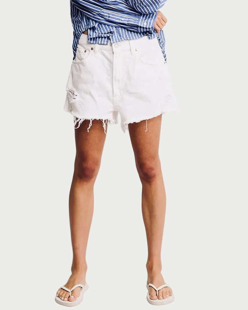 Woman wearing a blue striped shirt and white shorts on a plain background