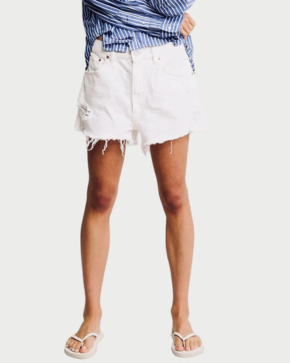 Woman wearing a blue striped shirt and white shorts on a plain background