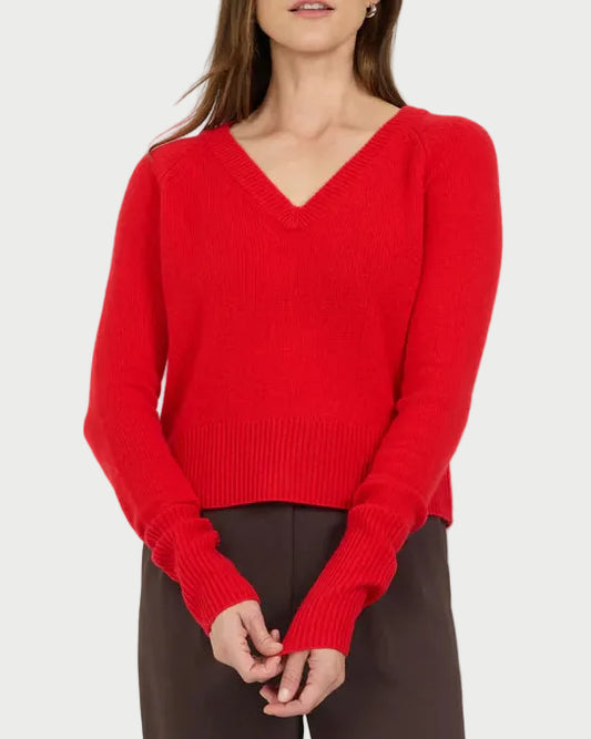Woman wearing a red sweater and brown pants on a white background