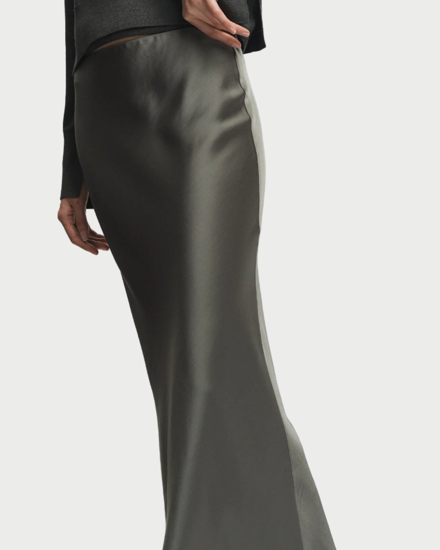 Person wearing a dark gray outfit with a satin skirt on a white background