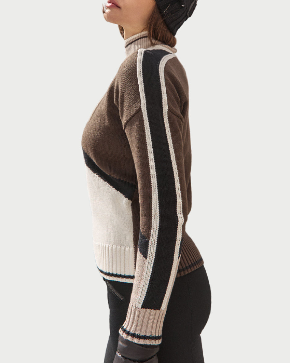 Person wearing a stylish sweater with a mountainous landscape in the background