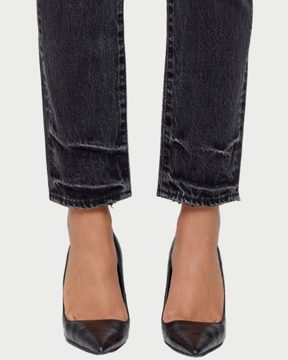 Black high-heeled shoes worn with black jeans on a white background