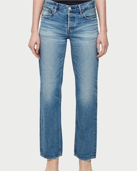 A person wears Moussy’s Millsboro Straight Low Jeans in light blue Japanese cotton denim with a straight leg, faded wash, and classic five-pocket design, standing barefoot against a white background.