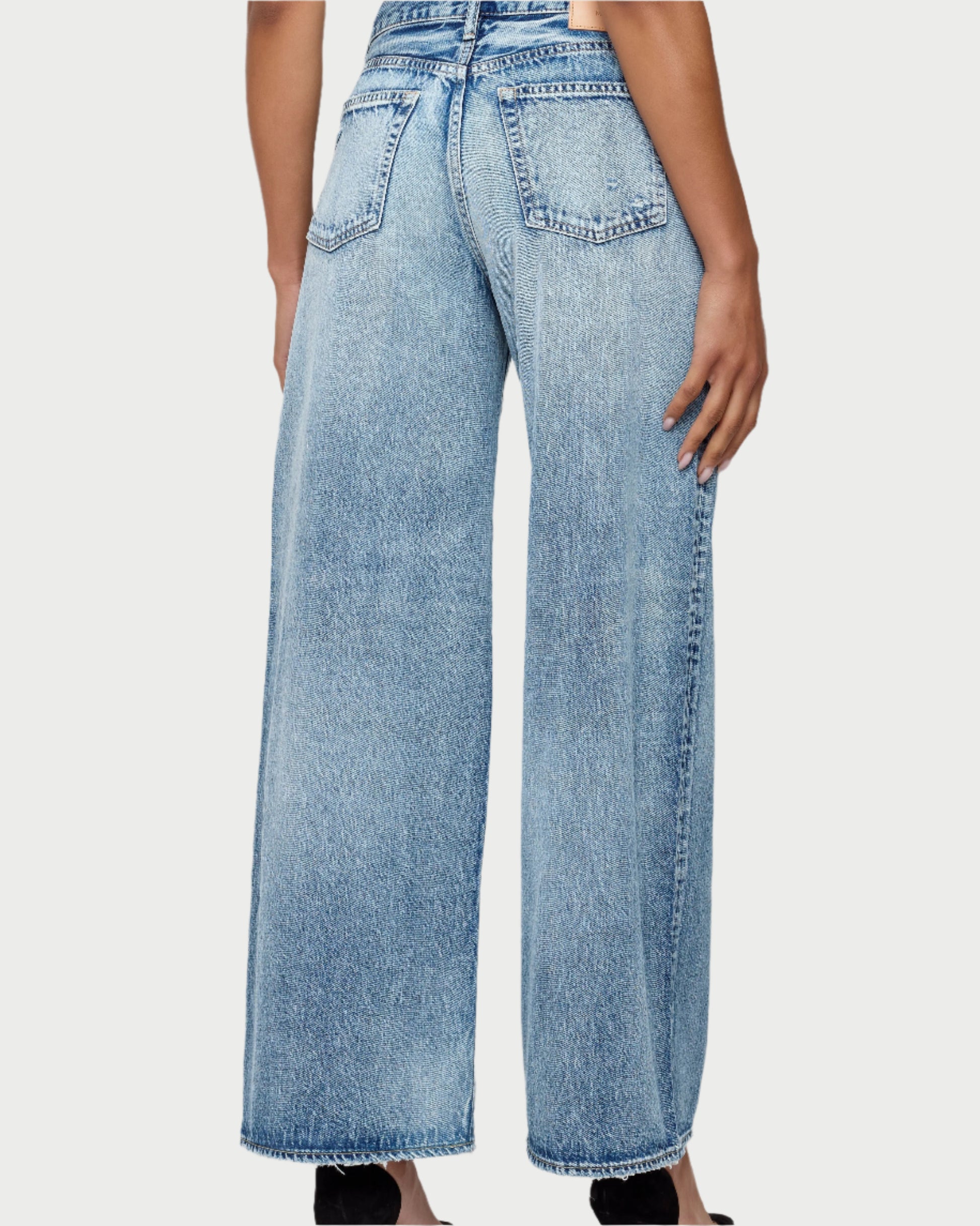 A person is seen from the back wearing the Moussy Lewes Super Wide Jeans in light blue Japanese cotton, featuring a low to mid-rise fit, visible pockets, and seam details, standing against a plain background.