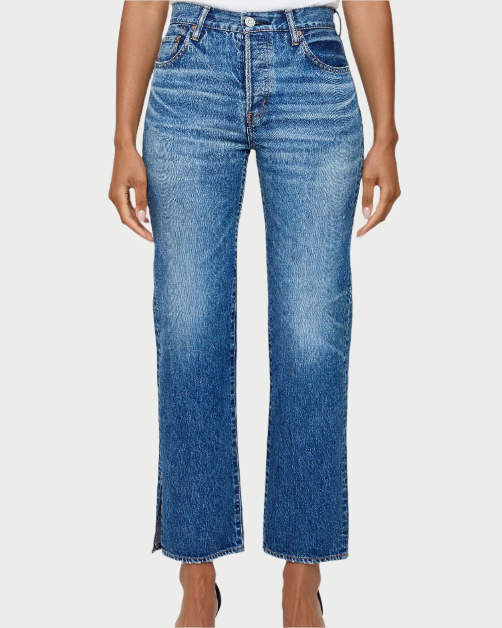 A person wearing Moussy Sunset Straight Jeans, crafted from Japanese cotton denim with a faded wash and slight side slits at the hem, stands against a white background.