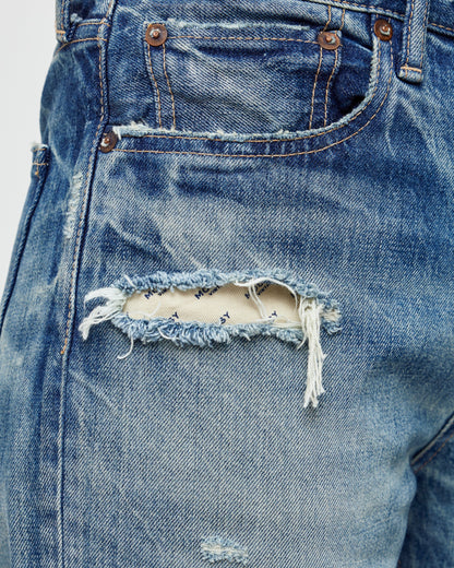 A close-up reveals a frayed tear on the front pocket of Moussy's Sayville Boys Jeans. The exposed Japanese denim adds a distressed, vintage vibe, while brass rivets reinforce the nearby area.