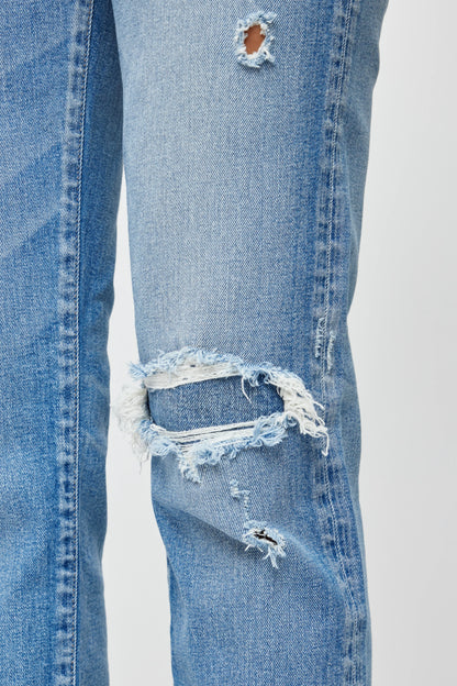 Close-up of a pair of blue jeans with multiple tears on a white background