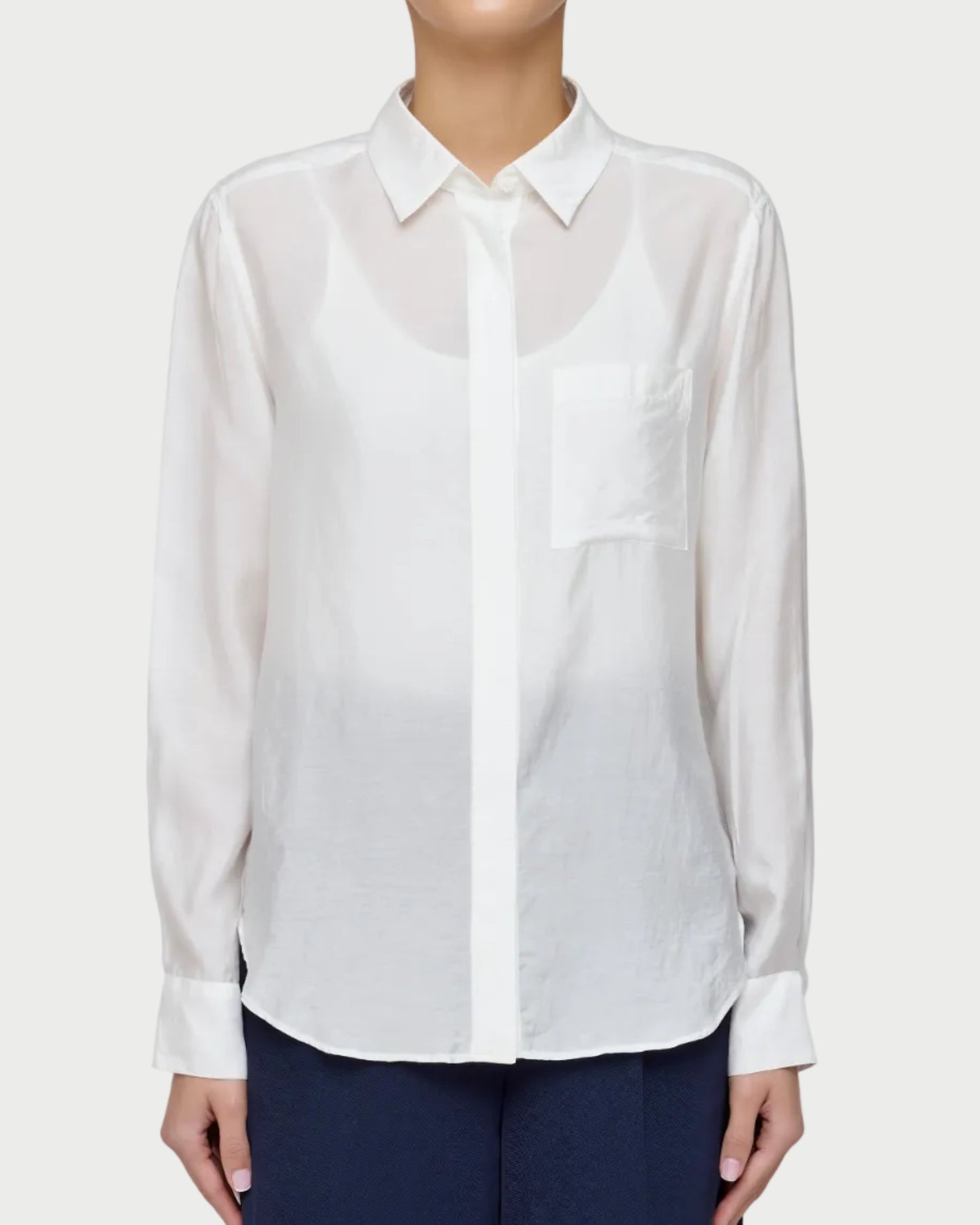 Person wearing a white shirt and navy pants on a plain background