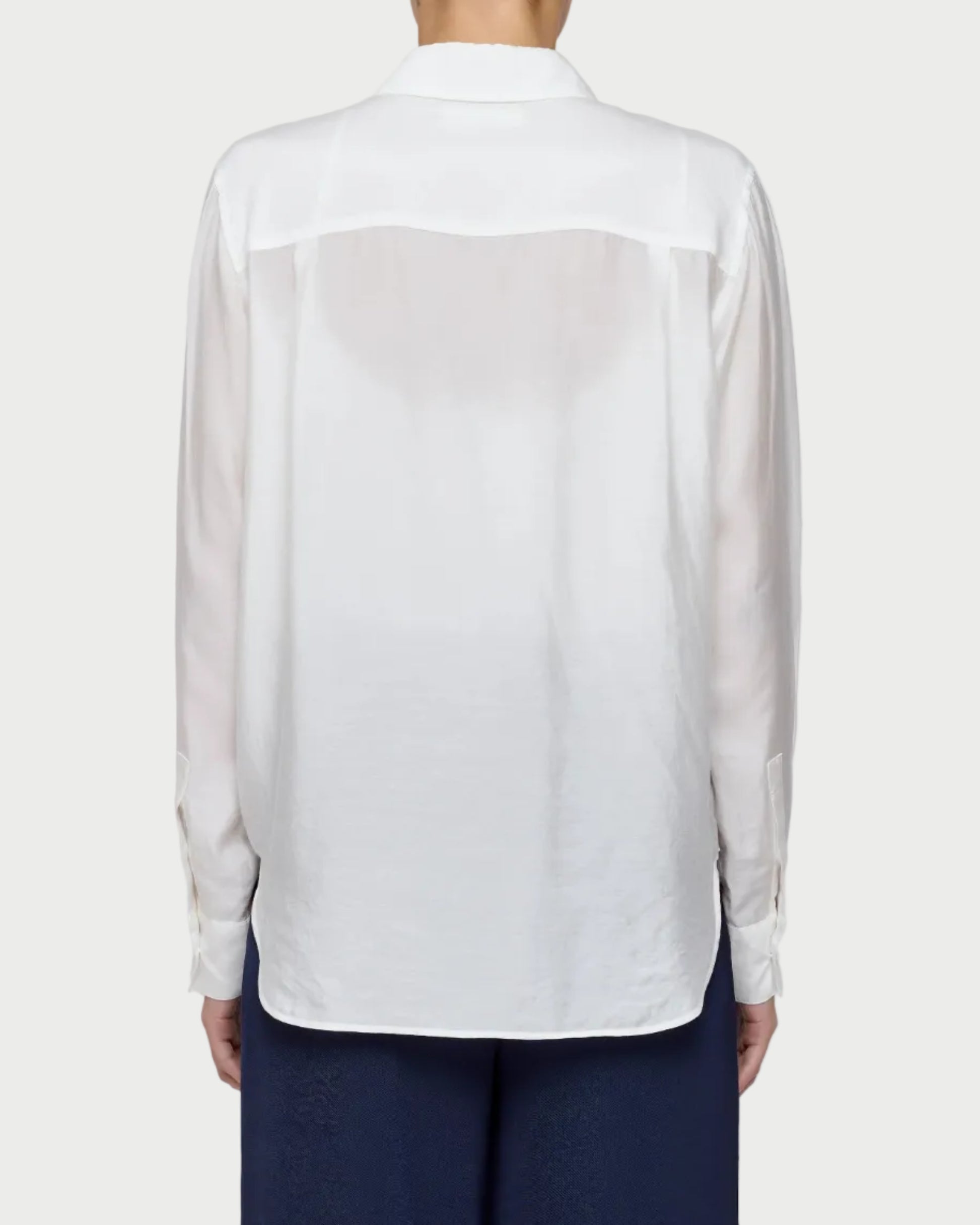 White sheer blouse over a navy outfit on a plain background