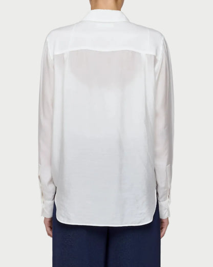 White sheer blouse over a navy outfit on a plain background