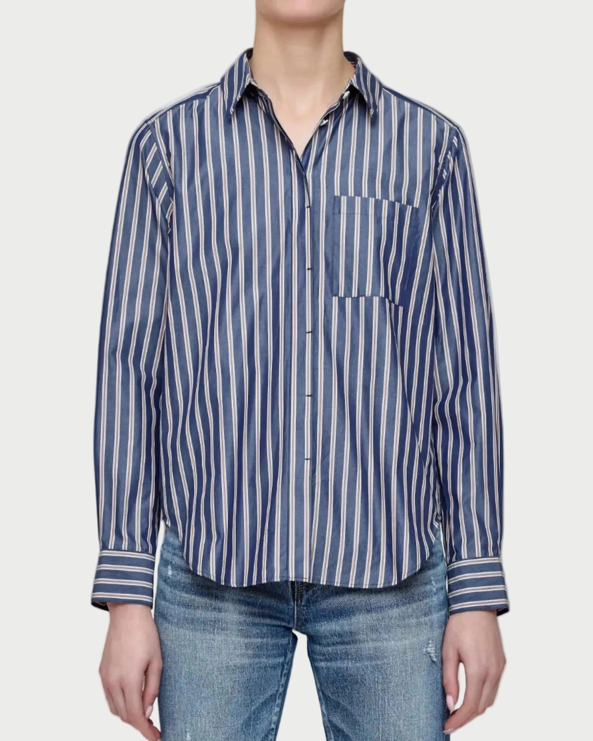 Person wearing a blue and white striped shirt with a pocket, standing against a plain background