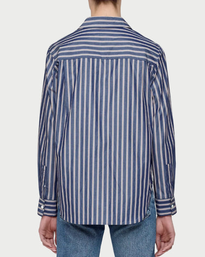 Person wearing a blue and white striped shirt and jeans on a plain background