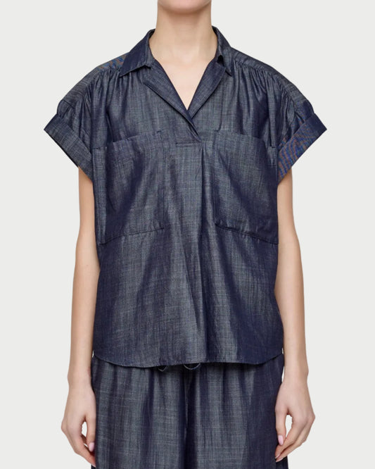 Person wearing a dark denim outfit on a plain background