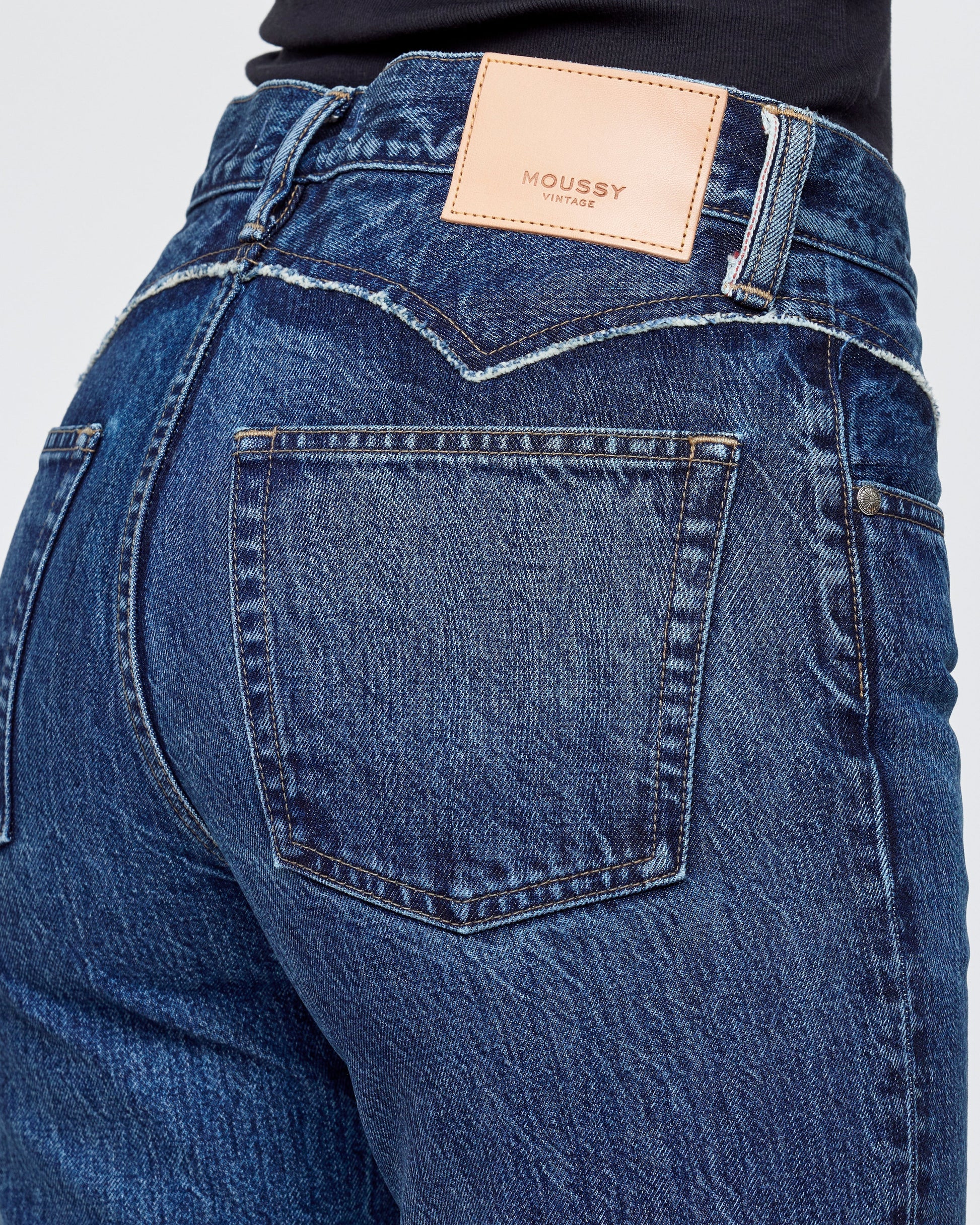 Close-up of blue jeans with a brand label on a white background