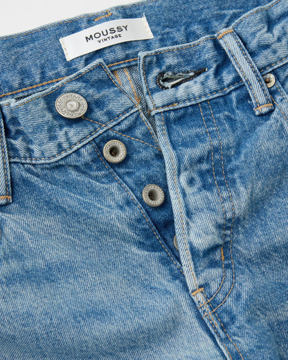 Close-up of blue jeans with a 'MOUSSY' label on a white background