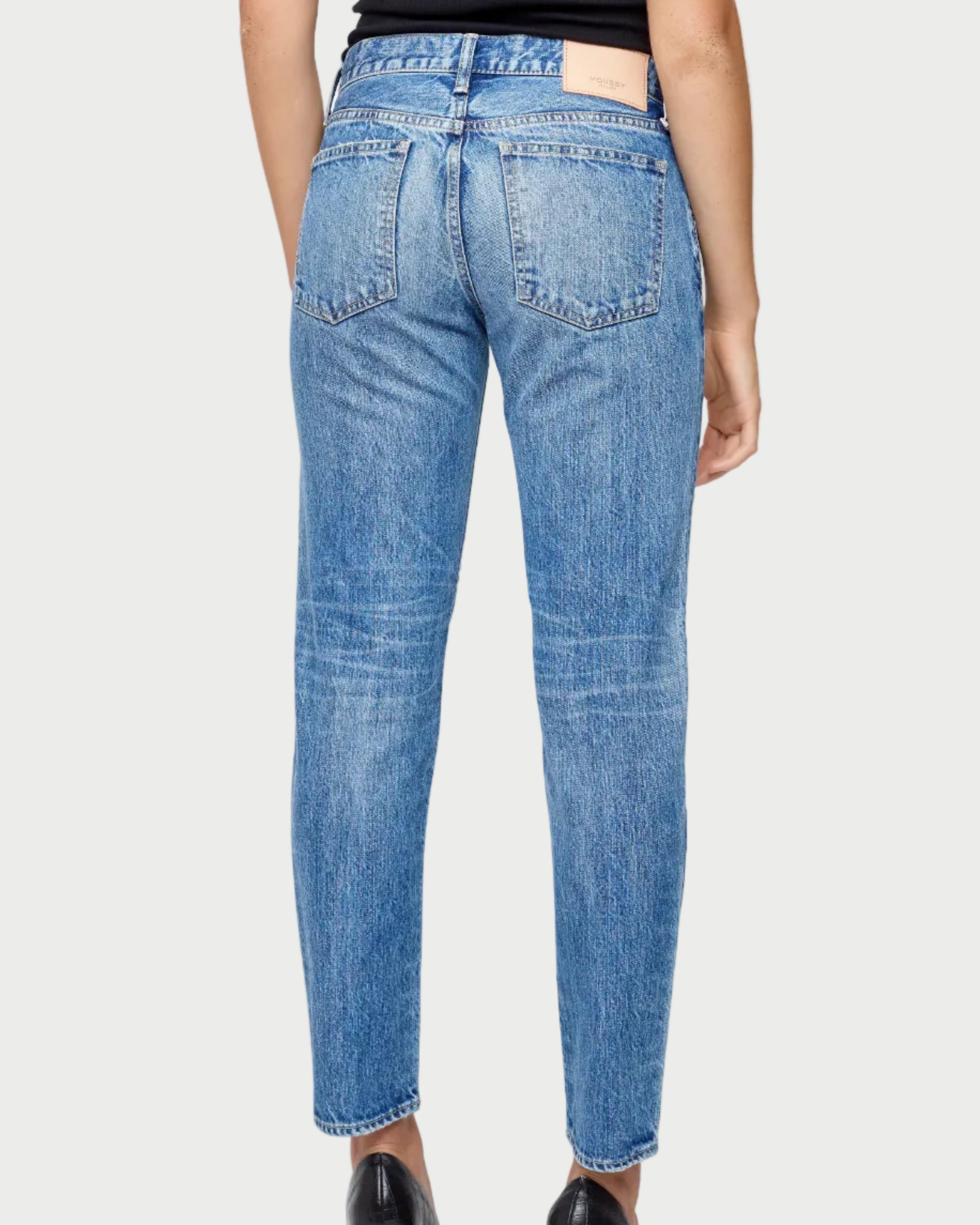 Person wearing blue jeans on a light gray background