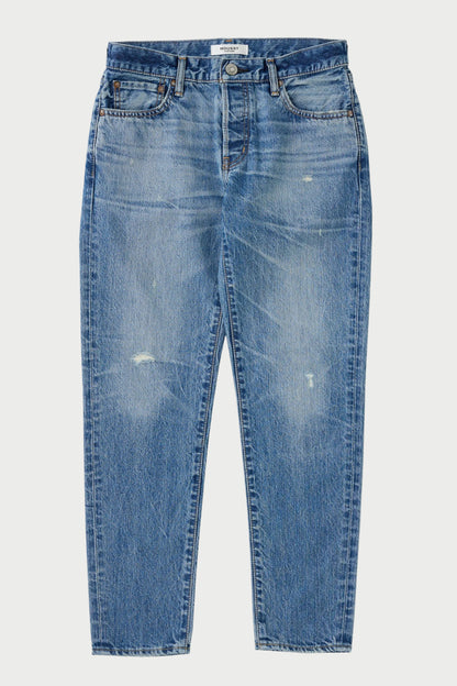 The Moussy Wrentham Tapered Jeans by Moussy are blue Japanese denim jeans with fading, light distressing, small rips, whiskering, a button closure, and five-pocket styling, shown laid flat on a white background.
