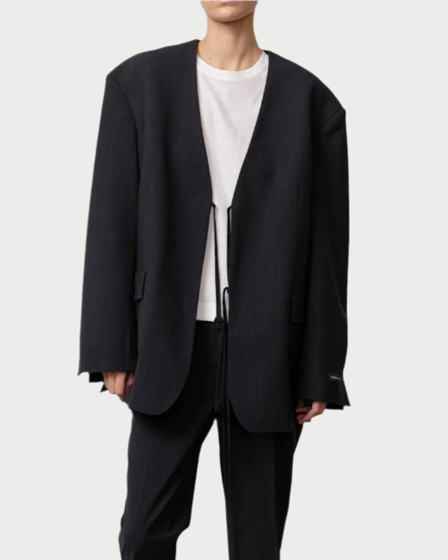 Person wearing a black suit with white shoes on a plain background