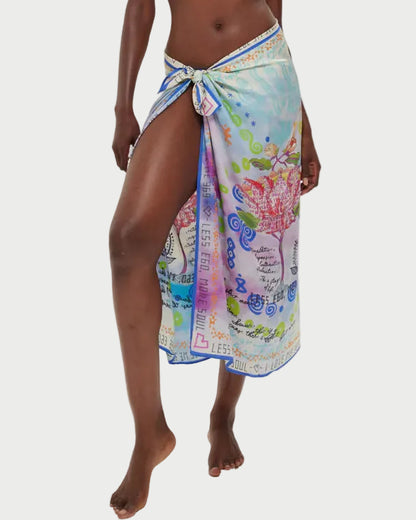 Woman wearing a colorful floral sarong over a white bikini on a white background