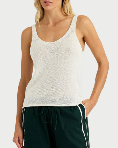 Woman wearing a white tank top and green pants with a white background
