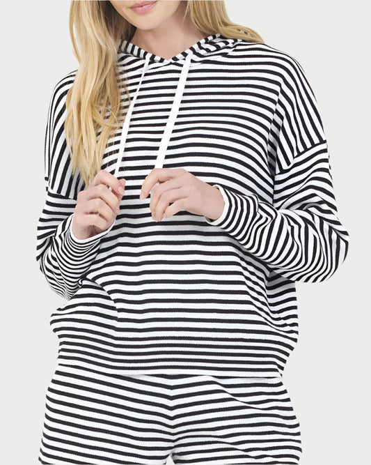 A woman with loose blonde hair, partly out of frame, wears the One Grey Day Stripe Warwick Hoodie and matching pants. This cotton-blend hoodie offers a lightweight layer for a casual look.