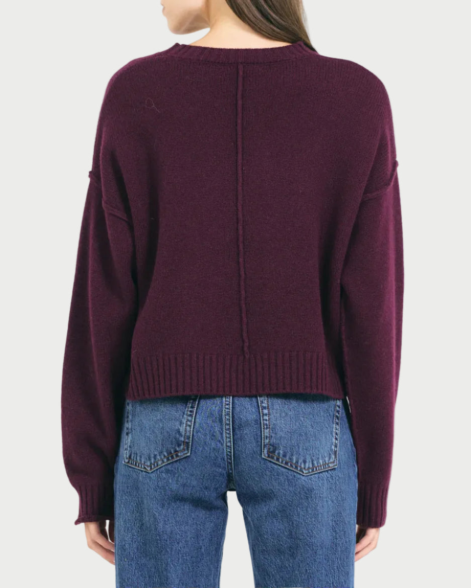 Person wearing a burgundy sweater and blue jeans on a white background