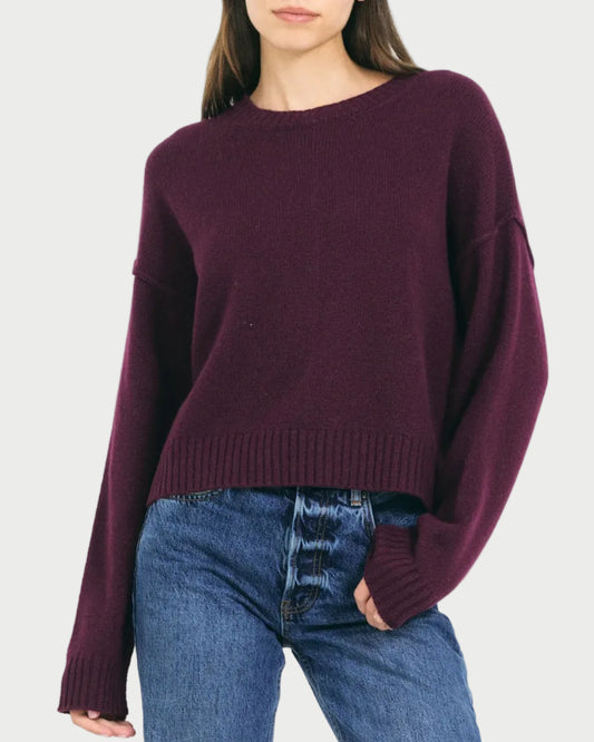 Woman wearing a purple sweater and blue jeans on a white background
